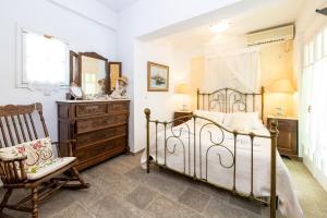 a bedroom with a bed and a chair and a dresser at Villa Areto in Kamares