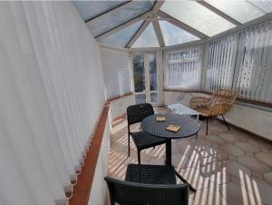 a screened in porch with a table and chairs at Relaxed Double bed with private bathroom, parking, WiFi and garden. in Leeds
