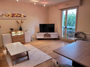 ein Wohnzimmer mit einem TV und einem Tisch in der Unterkunft Studio récent résidence Charles Quint in Gray