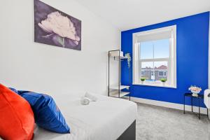 Dormitorio azul y blanco con cama y ventana en Sunshine Serviced Apartments by Happy Sunshine Stay en Goole