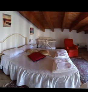 ヴィッラッジョ・モセにあるLa Casa degli Uliviのベッドルーム(白い大型ベッド1台、赤い椅子付)