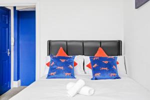 Cama blanca con almohadas azules y naranjas en Sunshine Serviced Apartments by Happy Sunshine Stay en Goole