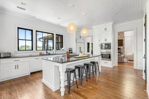 a kitchen with white cabinets and a large island with bar stools at Club Cottage 6 in Kiawah Island