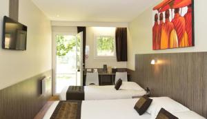 オンドルにあるThe Originals City, Hôtel Le Lodge, Bayonne Nordのベッド2台とテレビが備わるホテルルームです。