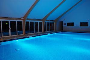 a swimming pool with blue lights in a building at Retallack Resort 4 bedroom lodge - Hot Tub for hire on request -Pool & Spa in Padstow