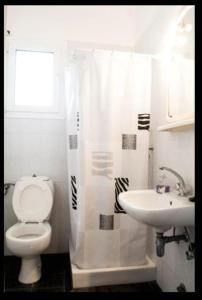 La salle de bains blanche est pourvue de toilettes et d'un lavabo. dans l'établissement Villa Mastiha , Komi Beach, à Kómi