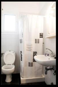 a white bathroom with a toilet and a sink at Villa Mastiha , Komi Beach in Kómi