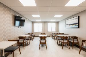 a dining room with tables and chairs and a flat screen tv at Garden Executive Hotel in South Plainfield