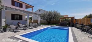 una piscina en un patio con sillas y una casa en Apartment Brioni Sea,Garden,Poll view 2 plus 2 80m2 tiki bar, en Peroj