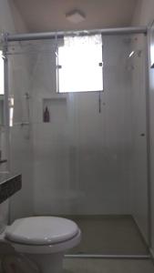a bathroom with a toilet and a glass shower at Flat em local tranquilo, com garagem compartilhada a dois quarteirões do centro histórico, 15 min de Tiradentes in São João del Rei