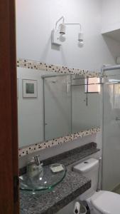 uma casa de banho com um WC e um lavatório de vidro em Flat em local tranquilo, com garagem compartilhada a dois quarteirões do centro histórico, 15 min de Tiradentes em São João del Rei
