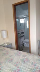 a bedroom with a bed and a bathroom with a mirror at Flat em local tranquilo, com garagem compartilhada a dois quarteirões do centro histórico, 15 min de Tiradentes in São João del Rei