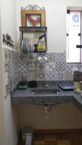 a kitchen counter with a sink and a mirror at Flat em local tranquilo, com garagem compartilhada a dois quarteirões do centro histórico, 15 min de Tiradentes in São João del Rei