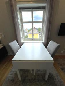 una mesa y sillas blancas en una habitación con ventana en Presttind - Studio apartment with free parking, en Narvik