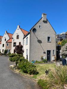 a house with a dog sitting in front of it at Mill Cottage in Lower Largo