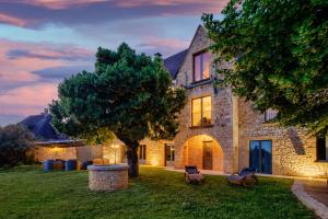 une maison en pierre avec un arbre dans la cour dans l'établissement Domaine de Ravat, à Sarlat-la-Canéda