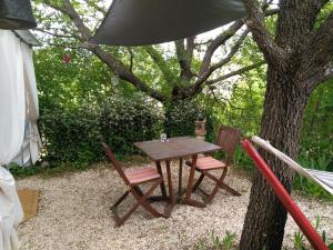 una mesa de madera y dos sillas bajo un árbol en Au Cabanon Chez Nath - chbre d'hôtes - gîte, en Varages