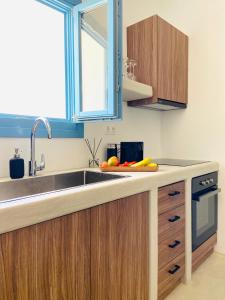 eine Küche mit Holzschränken, einem Waschbecken und einem Fenster in der Unterkunft Sun House Paros in Kampos Paros