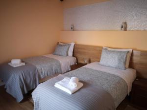 een kamer met drie bedden en handdoeken erop bij Feather House in São Bartolomeu