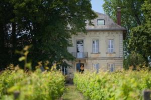 an old house with a woman standing in front of it at CHATEAU BELAIR-Séjour Prestige in Sainte-Croix-du-Mont