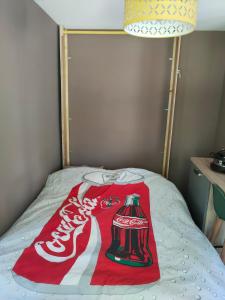 a cocacola blanket on top of a bed at La jurassienne in Champagnole