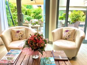 una sala de estar con 2 sillas y una mesa con un jarrón de flores en Hotel Alfieri en Sirmione