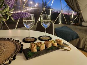 two glasses of wine and a plate of food on a table at Glamping Kaszuby in Pomysk Wielki