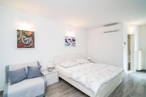 ein weißes Schlafzimmer mit einem Bett und einem Stuhl in der Unterkunft Studio Apartment Lapad in Dubrovnik