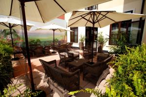 een patio met tafels, stoelen en parasols bij Hotel Croce Bianca in Asiago