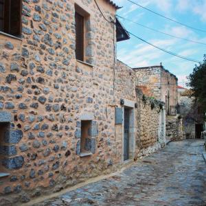 a stone building with windows on a street at All stone, everything.. in Areopolis