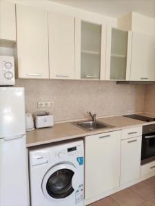 een witte keuken met een wasmachine en een wastafel bij Private Apartment 49 in Prestige Fort Beach Hotel in Sveti Vlas