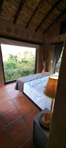 a bedroom with a bed and a large window at Hacienda Mawaka in Ráquira