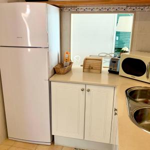 a kitchen with a white refrigerator and a microwave at Es Cucó in Cala Galdana