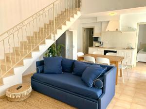 a living room with a blue couch and a staircase at Es Cucó in Cala Galdana