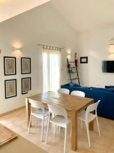a living room with a wooden table and white chairs at Es Cucó in Cala Galdana