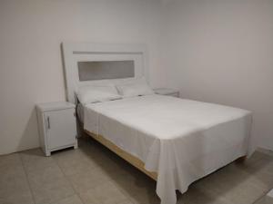 1 dormitorio con cama blanca y mesita de noche en Casa M&J Cd. Juarez en Ciudad Juárez