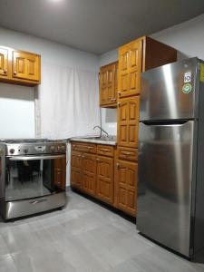 una cocina con nevera de acero inoxidable y armarios de madera en Casa M&J Cd. Juarez, en Ciudad Juárez