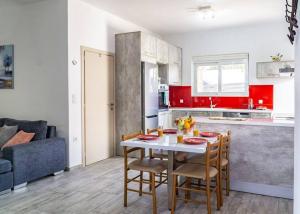 uma cozinha com armários vermelhos, uma mesa e cadeiras em ARTEMISSIA New Well Sided Modish House em Kissamos