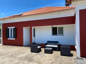 a red and white house with chairs and a patio at Brazão Guest House in Santana
