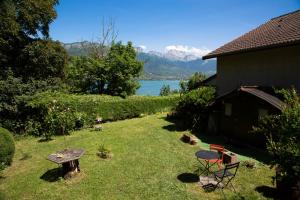 une cour avec une table et des chaises ainsi qu'un lac dans l'établissement Maison à 30 mètres du lac et piste cyclable, à Sévrier