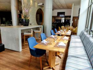 un restaurante con mesas de madera y sillas azules en Best Western Premier Maceió en Maceió