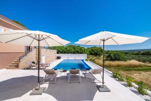a patio with two umbrellas and a swimming pool at Villa Matea - heated pool, peace, view in Pridraga