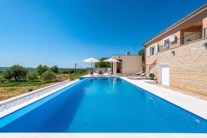 a swimming pool in front of a house at Villa Matea - heated pool, peace, view in Pridraga