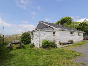 a white cottage with a picnic table in the yard at Y Bwthyn in Dinorwic