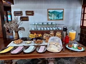 una mesa con muchos platos de comida. en Pousada Cascata, en Casimiro de Abreu