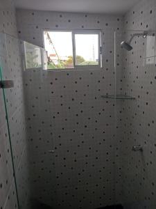 y baño con ducha acristalada y ventana. en Casa Aluna en Barranquilla