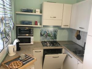 La cuisine est équipée de placards blancs et d'un four avec plaques de cuisson. dans l'établissement Estate Famiglia Andora, à Marina dʼAndora