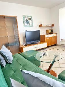 ein Wohnzimmer mit einem grünen Sofa und einem TV in der Unterkunft Villa Moare in Koper