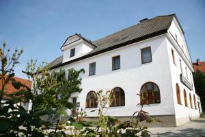 un edificio blanco con techo negro en Pension-Metzgerei Hofer, en Inning am Holz