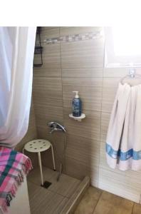 uma casa de banho com um chuveiro, um banco e uma toalha em Amaryllis sweet home em Pirgos